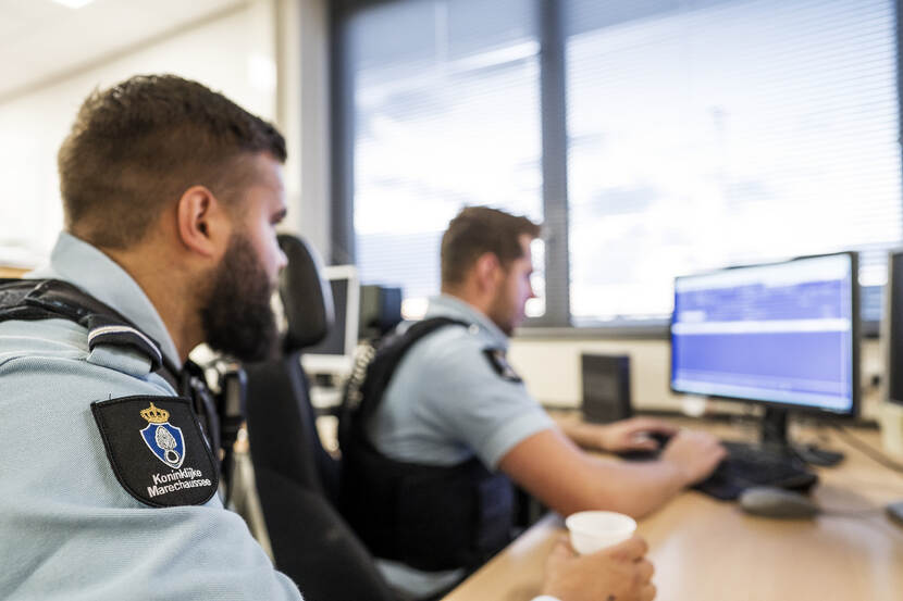 2 marechaussees voeren een mutatie in op een computer.