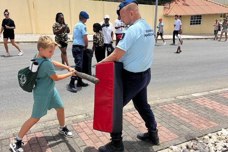 Op de open dag op marinebasis Parera slaat een kind met een knuppel op een luchtkussen dat een collega vast heeft.