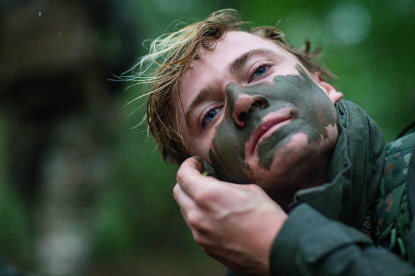 Een collega brengt camouflage aan op zijn gezicht.