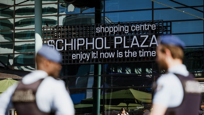 Marechaussees voor bord Schiphol Airport.