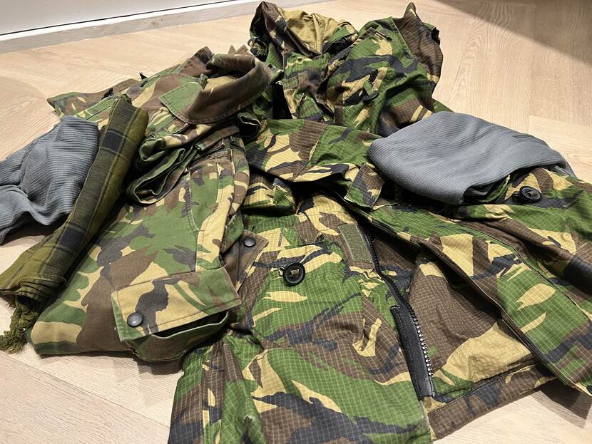 Een stapel militaire uniformen en accessoires.
