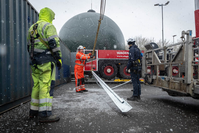 Medewerkers op de grond in de sneeuw met de stalen bliksemafleider.