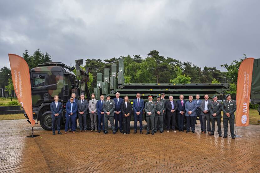 20 militairen en burgermedewerkers poseren voor een militaire vrachtwagen met oplegger