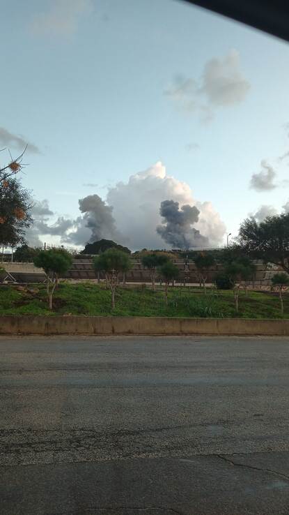 Een groen landschap met lichte heuvels in Zuid-Libanon met in de lucht inktzwarte rookwolken van een raketaanval.