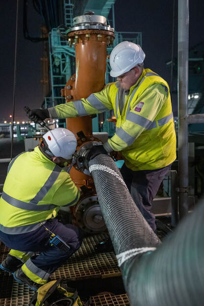 Een man met een gele veiligheidsjas draait een moer vast.