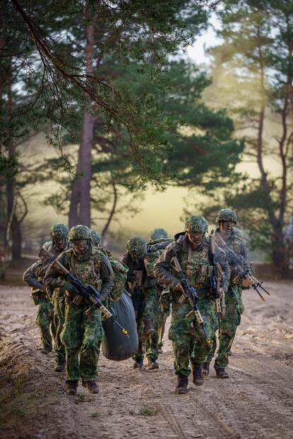 Een groepje reservisten doet verplaatsing te voet, door mul zand.