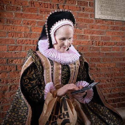 Re-enactor met ouderwetse kledij en een mobiele telefoon in haar hand.