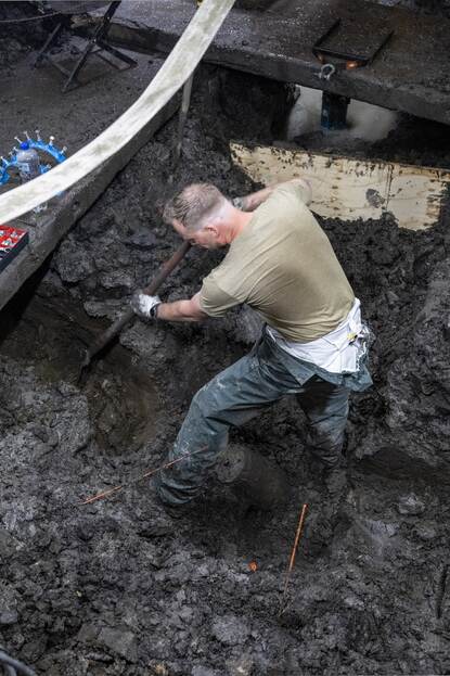 Man graaft drassige klei weg in de bouwput.