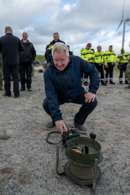 Man zit gehurkt bij het apparaat, waarop gedrukt moet worden om het explosief te laten detoneren.
