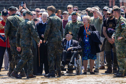 Drie fuseliers staan met een nat uniform op het zand.