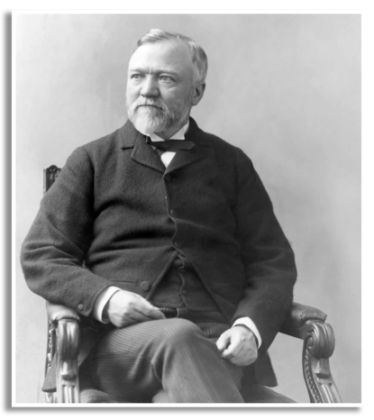 Alfred Carnegie poseert zittend in een stoel.