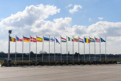 Een zestiental vlaggen wappert naast elkaar. Aan het einde de NAVO-vlag.