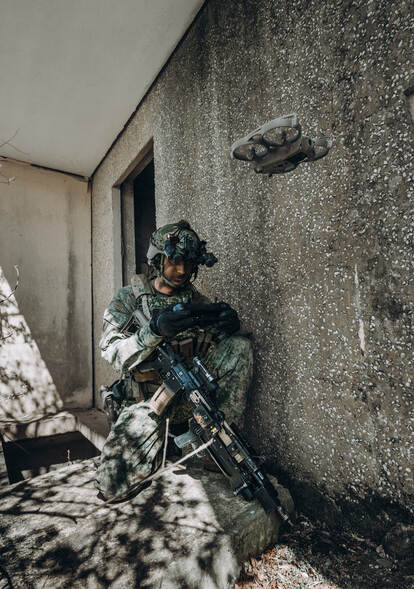 een militair zit naast een muurtje.