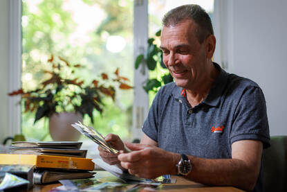 Een portretfoto van Arthur waarbij hij door oude fotoboeken bladert.