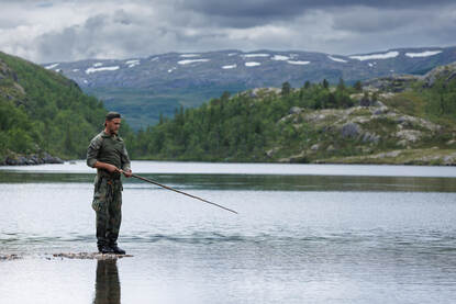 Een vissende militair en een vis die gefileerd wordt.