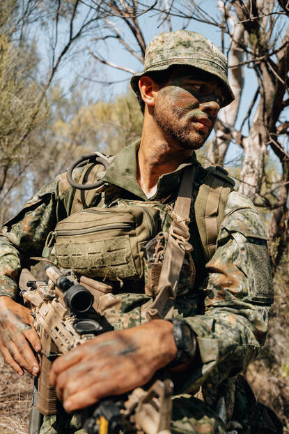 Marinier in gevechtskleding met wapen in hand in de bush tijdens oefening.
