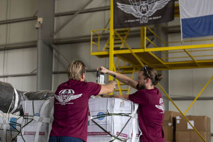 Links een foto waarop militairen een bundel inpakken. Rechts een militair die een pakket inspecteert voordat het aan boord gaat.