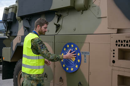 Militair plakt een EU-sticker op een militair voertuig