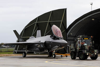Een F-35 in een shelter en een F-35 wordt de shelter uitgereden.