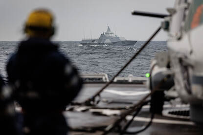 Bemanningsleden kijken naar een Zweeds oorlogsschip dat voorbij vaart.
