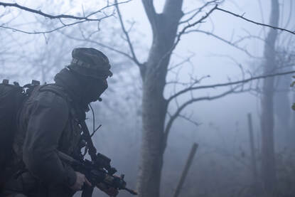 Mariniers op verkenning in een mistig bos en lopend door een weiland.