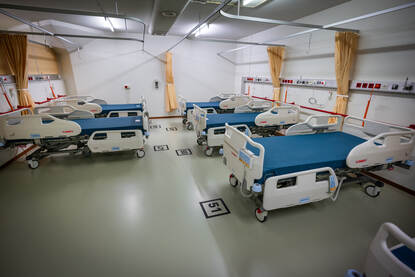 Links de nieuwe bedden in een ziekenzaal. Rechts de oude bedden op een stapel.