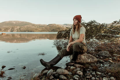 Majoor Marie-José Spek zit in outdoorkleding aan de rand van een meer in Noorwegen.
