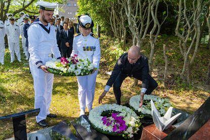 Marinemensen leggen een krans bij een monument.