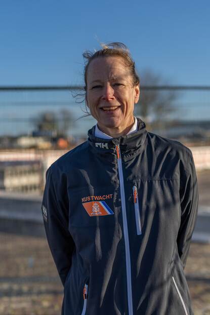 Een vrouw poseert buiten in de wind.