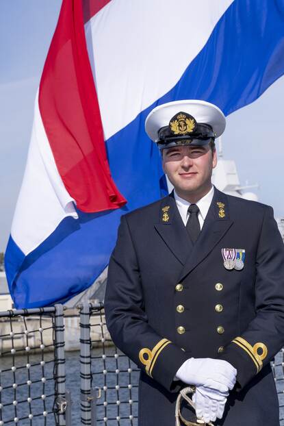 Militair poseert voor Nederlandse vlag.