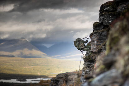 Links laat een marinier zich abseilend van een berg zakken. Rechts handen die een kaarthoekmeter gebruiken op een landkaart.