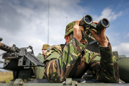 Illustratiefoto van landmachter die door zijn verrekijker tuurt.