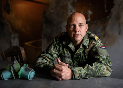 Sergeant-majoor Annik Timmerman zit aan tafel en kijkt recht in de camera.