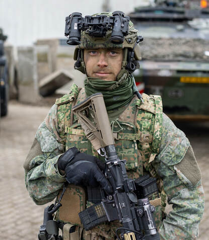 Portretfoto van Luca in vol ornaat, met wapen en camouflageverf op zin gezicht.