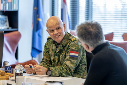 Militair zit aan tafel en is in gesprek met andere man in burger.