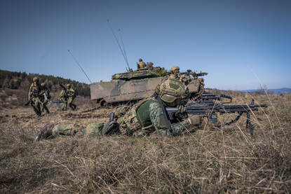 Een militair ligt in het terrein en legt aan.