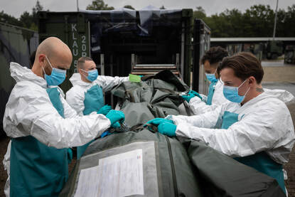 Vier militairen bij een lijkzak.