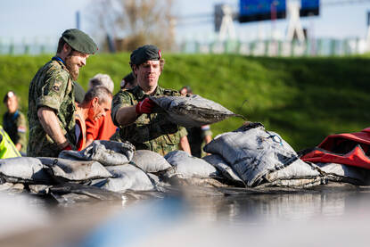 2 militairen leggen zandzakken neer.