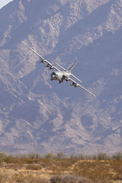 Een C-130 maakt een scherpe bocht om te landen, met een berg op de achtergrond.