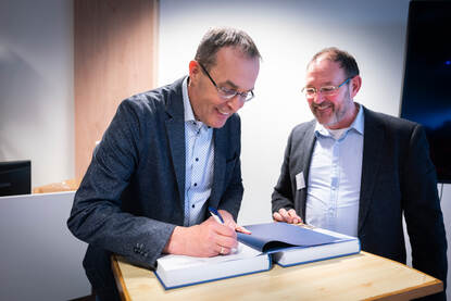 Links: Mensen wachten op hun beurt om hun boek gesigneerd te krijgen. Rechts: Ivo de Jong signeert een boek.