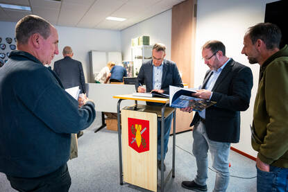 Links: Mensen wachten op hun beurt om hun boek gesigneerd te krijgen. Rechts: Ivo de Jong signeert een boek.