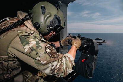 Een militair zit achter een van de boordwapens.