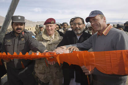 Links: auto’s en een ezelkar op straat in een Iraakse stad. Rechts: Vier mannen naast elkaar bij het doorknippen van een oranje lint.