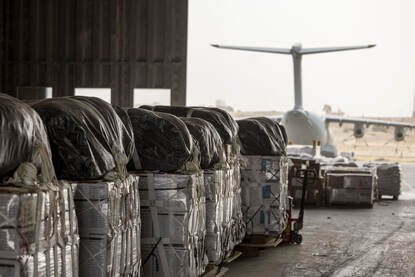 Links een foto van een ingepakte parachute op een bundel. Rechts een rij bundels in een hangar met een Duitse A400M op de achtergrond.
