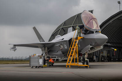 Links: Onderhoudspersoneel werkt aan een F-35 die voor een shelter staat. Rechts: Bewapeningspersoneel is bezig met de controle van een Sidewinder-luchtdoelraket.