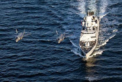 Afbeeldingen van een Chinook, een NH90, een MQ-9 Reaper en twee F-35’s die over een marineschip vliegen.