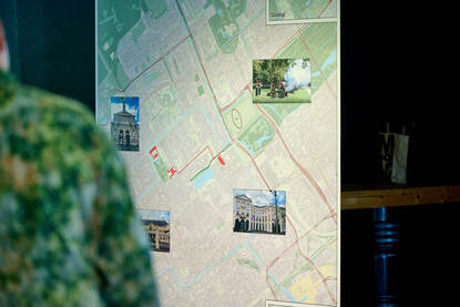 Een plattegrond van Den Haag met daarop afbeeldingen van verschillende locaties. Hierop zijn onder meer Paleis Noordeinde en de Koninklijke Stadsschouwburg te zien.