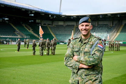 Portretfoto van adjudant Johan Blom. Achter hem staat de vaandelwacht opgesteld.