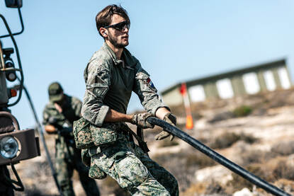 Een militair sleurt met een grote kabel.