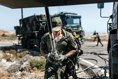 Een militair is bezig met de aansluiting van een grote kabel.